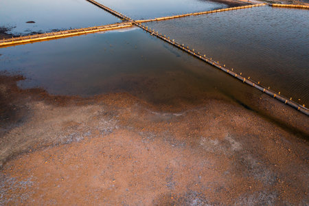 Aerial view of salt pans at sunset showcasing water and land contrastの写真素材