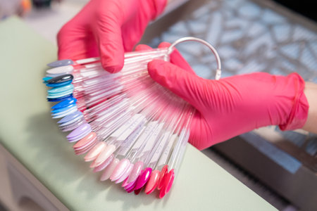 Nail master holding a collection of nails color polish samples. A palette of transparent tips with different colors.の写真素材