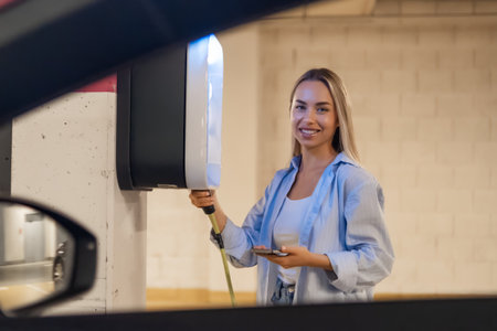 Woman uses a charging station to power her electric vehicle while parked indoors