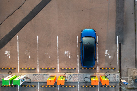 Top view of blue electric car is plugged into a charging point at a parking lot, drawing power efficientlyの写真素材