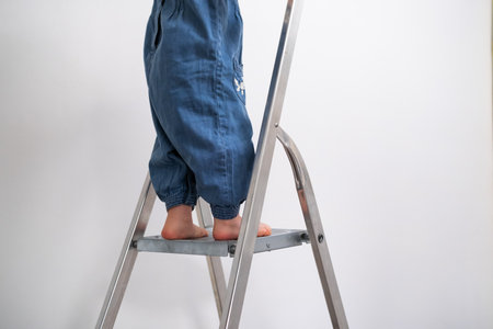 Tiny childs feet climbing a ladder, close up of little girl going up to help with painting