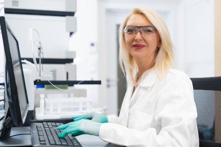 Senior scientist sitting at a computer with an HPLC instrument in the background. Concept of...
