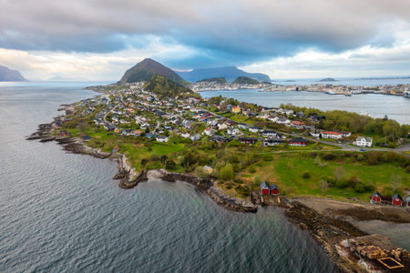 Alesund waterfront with traditional Nordic architecture, peaceful harbor, and lush mountain backdrop in soft daylight.の写真素材