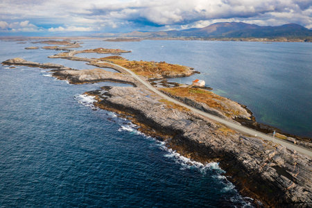 Extensive Atlantic ocean road gracefully weaves across small islands and over narrow channels. Norway challenging coastal geography under cloudy skyの写真素材