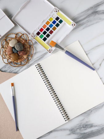 Marble desk creative office with water colors, brushes and blank notepad or papers to start painting or write a text.の写真素材