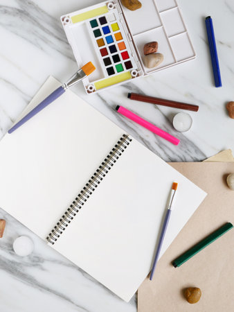 Marble desk creative office with water colors, brushes and blank notepad or papers to start painting or write a text.の写真素材