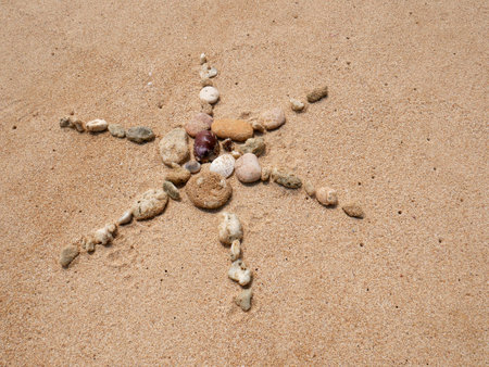 Set of colorful pebbles forming a star on beach sand backgroundの写真素材