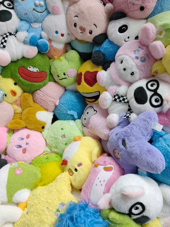 A colorful array of plush toys lines in a cozy toy store,. A variety of plush toys, including bears and bunnies, are neatly arranged on wooden shelves.の写真素材