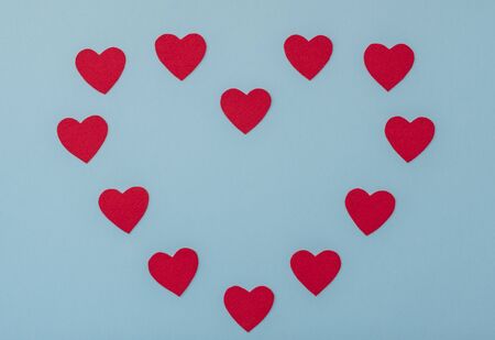 Valentine's Day blue background with red hearts. Valentine greeting card. Flat lay style.