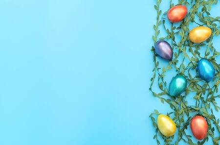Decorated Easter eggs lie on green leaves on the blue background. Happy Easter holiday concept. Greeting, invitation card. Flat lay styleの写真素材