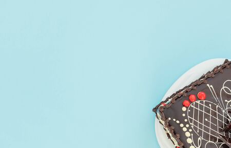 Chocolate cake with white and red cream on blue background. Holiday concept. Flat lay style with...