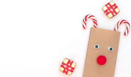 Christmas deer made of craft bag and two Xmas canes with gift boxes on white background. New Year...
