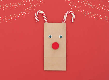 Christmas deer made of craft shopping bag and two Xmas canes on red background. New Year greeting card. Christmas and New Year concept.の写真素材