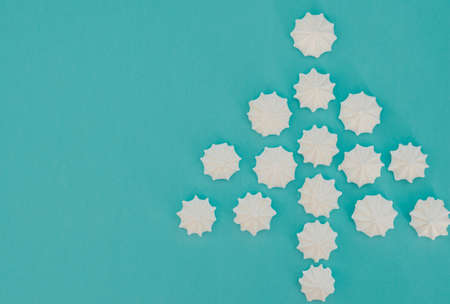 Christmas tree made with white meringues on light blue background.