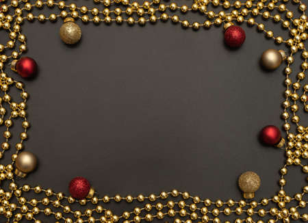 Christmas black background with golden beads and red and golden Xmas decorations. Flat lay style....