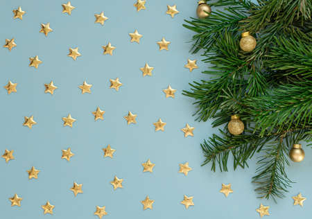Christmas, New Year or winter blue background with fir tree branches, small gold stars and balls....
