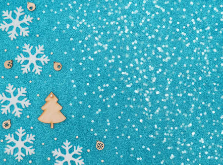 Christmas tree and wooden decorations with snowflakes and beads on blue background with white snow. New Year greeting card. Christmas, New Year concept. Flat lay style with copy space.の写真素材