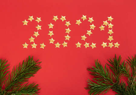 Christmas, New Year or winter red background with fir tree branches and small gold stars. Xmas and Happy New Year holiday concept. Christmas greeting or invitation card. Flat lay, top view style.の写真素材
