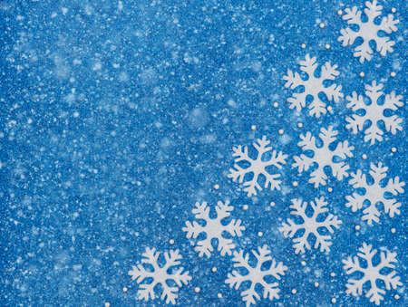 Christmas or winter blue background with white snowflakes, beads and snow. New Year greeting card. Christmas, New Year or winter concept. Flat lay style with copy space.の写真素材