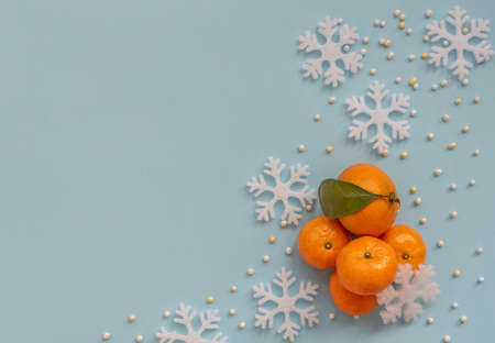 Christmas blue background with orange tangerines and white snowflakes. New Year greeting card. Flat lay style.の写真素材