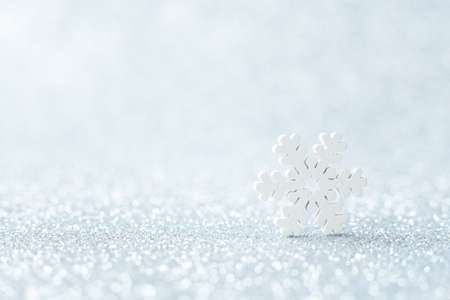 White snowflake on silver blurred background. Selective focus. Macro, minimalism concept. Christmas or winter greeting card, poster. Image for notebook cover. Xmas and Happy New Year holiday.の写真素材