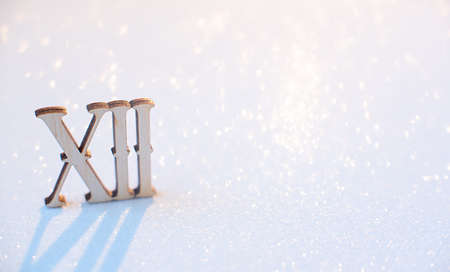 Wooden twelve Roman number on white background with glow bokeh. Selective focus. Macro, minimalism...