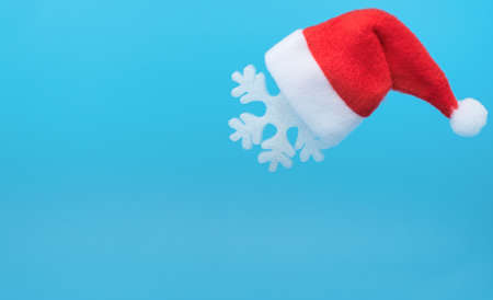 Santa Claus hat on snowflake against pastel blue background. Minimal winter concept. Christmas or winter greeting card, poster. New Year holiday.の写真素材