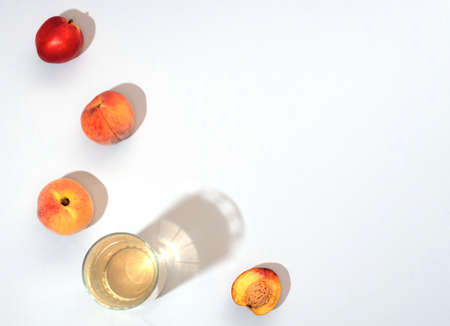 Summer scene with peaches, nectarines and glass of peach juice on white background. Flat lay style with copy space. Summertime conceptの写真素材