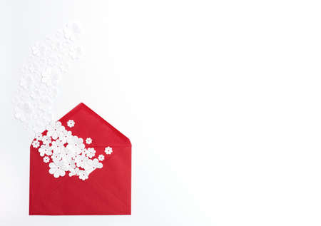 Red envelope with white paper flowers in it on white background. Greeting or invitation card. Flat lay style with copy space for your text. Paper artの写真素材