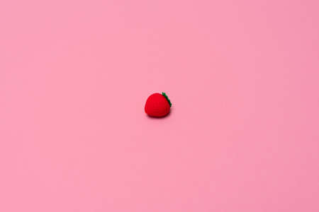 Small eraser in the form of strawberry on pink background. Summertime, minimalism concept. Flat lay style with copy spaceの写真素材