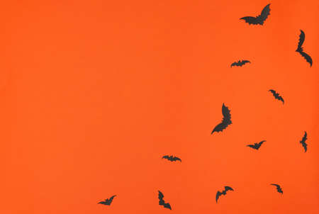 Halloween concept. Black paper bats on orange background. Greeting or invitation card. Flat lay style with copy space. Top viewの写真素材