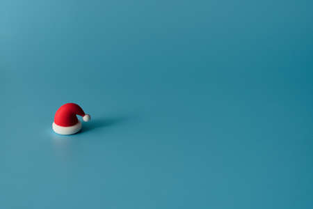Small Christmas hat on blue background. Greeting or invitation card. Holiday minimalism conceptの写真素材