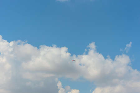 Bright blue sky with white clouds and a flying plane. Travel concept