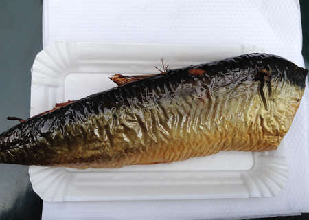 Appetizing hot smoked fish herring. Street food, takeout concept