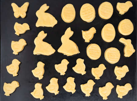 Cookies cut out from dough for Easter day on baking tray. Happy Easter concept. Process of making...