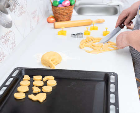 Senior woman hands cut out from dough pastry cookies for Easter day. Happy Easter concept. Process...