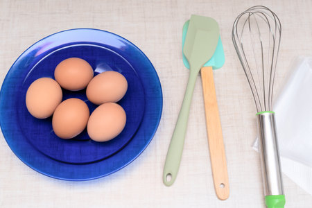 Eggs on blue plate and kitchen appliances are ready for making homemade cake. Selective focus. Process of cooking at home concept. High quality photoの写真素材