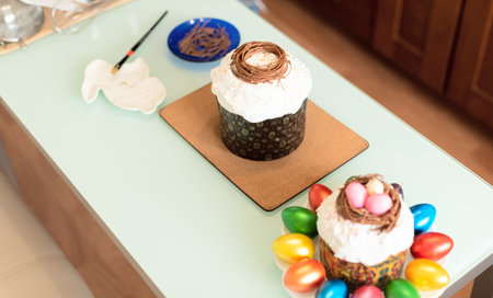 Homemade Easter cake on table during decorating it by chocolate and small painted eggs. Selective...