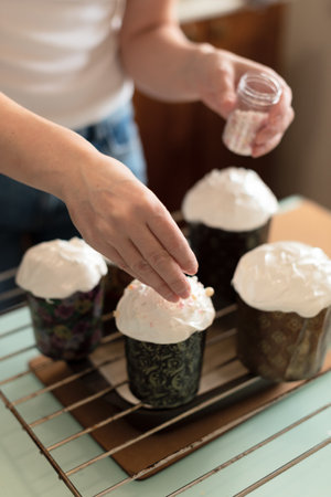 Woman making homemade Easter cake at home decorating it with small sprinkles. Selective focus. Happy...