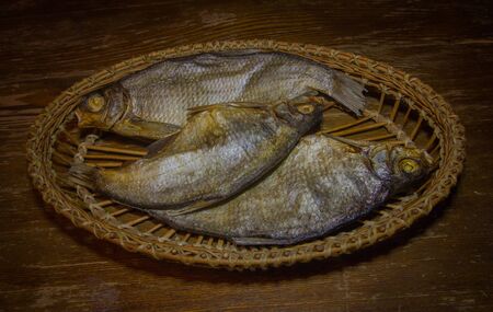Dried fish in a wicker dish on a wooden table