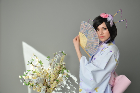 A girl in a yukata next to cherry twigsの写真素材