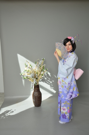 A girl in a yukata next to cherry twigsの写真素材