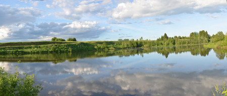 Spring summer landscape blue sky clouds Narew river boat green trees countryside grass Poland water leavesの写真素材