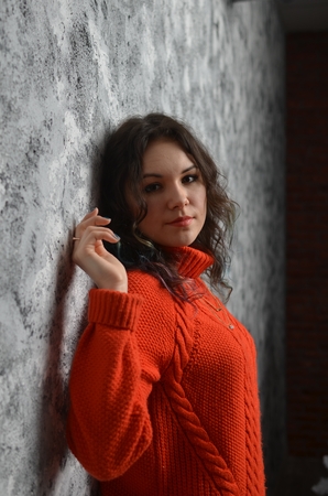 Sensual beautiful girl posing in red sweater. Girl with long curly hair.の写真素材