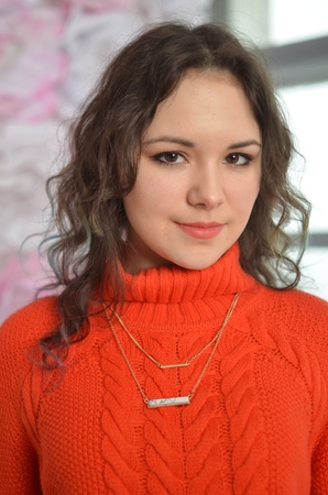 Sensual beautiful girl posing in red sweater. Girl with long curly hair.の写真素材