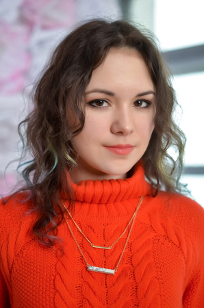 Sensual beautiful girl posing in red sweater. Girl with long curly hair.の写真素材