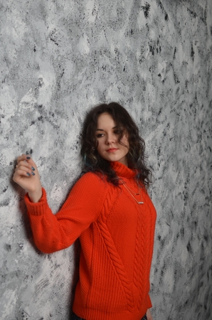 Sensual beautiful girl posing in red sweater. Girl with long curly hair.の写真素材