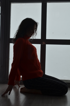 Sensual beautiful girl posing in red sweater. Girl with long curly hair.の写真素材