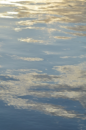 reflection of blue sky with white clouds in water, abstract background.の写真素材