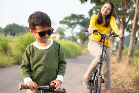 A beautiful mother playing a bicycle with her son on the edge of a paddy field in the countrysideの写真素材